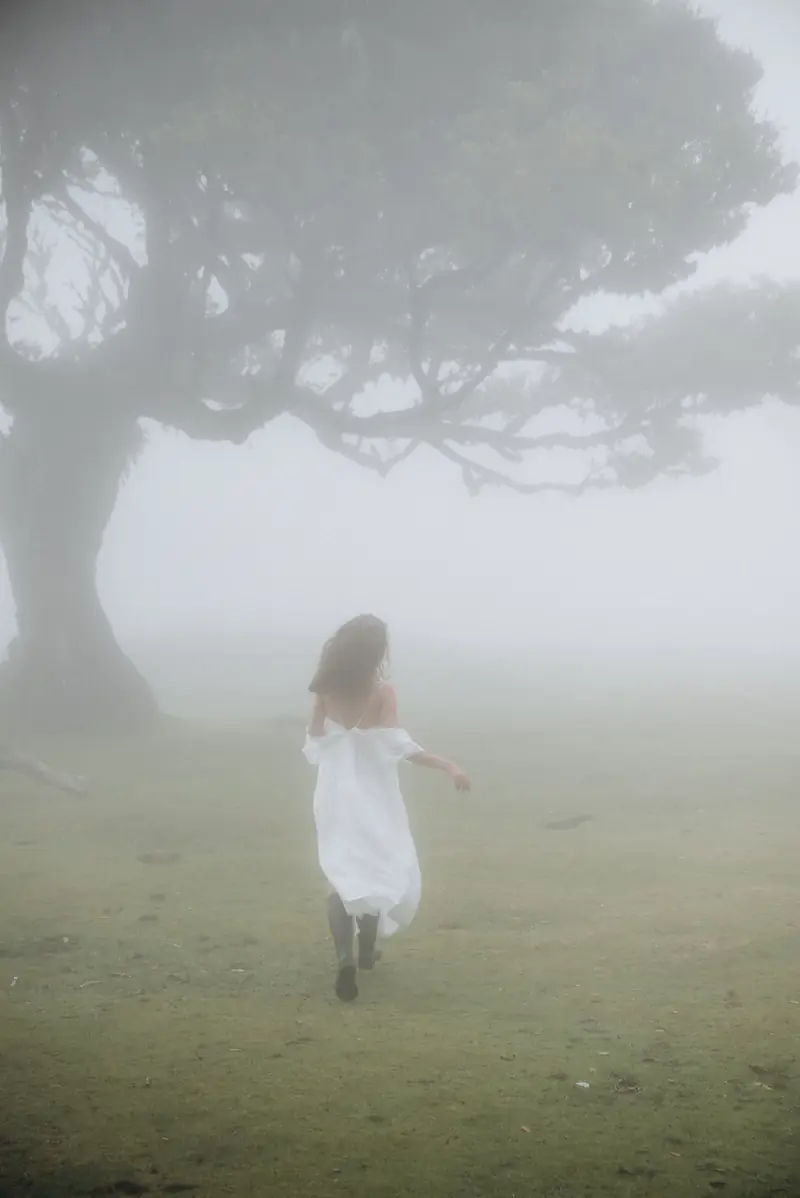 A woman running through the fog in Fanal forest